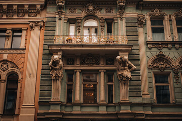 Fototapeta premium Vintage facade of an ancient building with windows. Stone statues of historical architecture