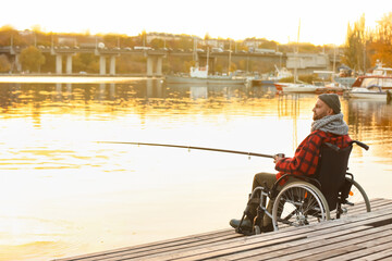 Man in wheelchair drinking hot tea while fishing on river