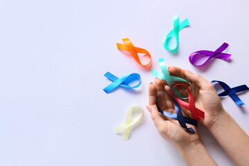Female hands with different awareness ribbons on white background. World Cancer Day