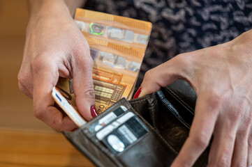 Close-up of a woman's hand putting money into a wallet