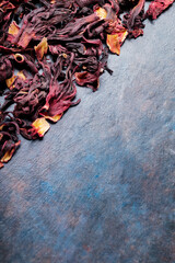 Flowers red hibiscus tea. Dry hibiscus petals on a dark background. Karkade, red tea, aromatic hibiscus tea. Top view. Copy space