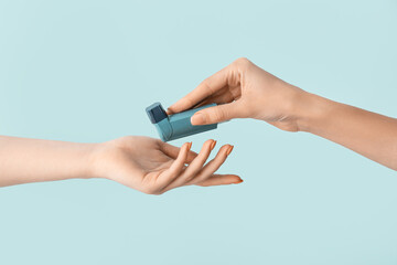 Female hands with asthma inhaler on blue background