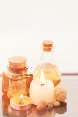 Fototapeta na wymiar Concise spa composition with oil flasks and candles on beige background.