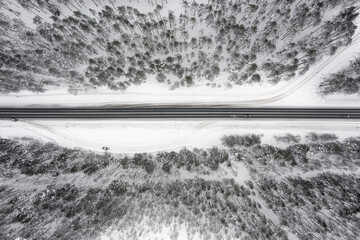 Aerial top-down winter view of a road passing through a snow-covered pine forest, Karelia, Russia