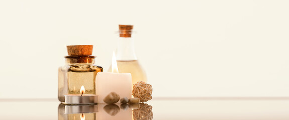 Concise spa composition with oil flasks and candles on beige background.