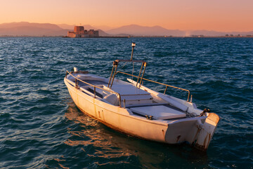 Sunset seascape with a boat on the water in front of Mpourtzi fortress, Nafplion, Greece