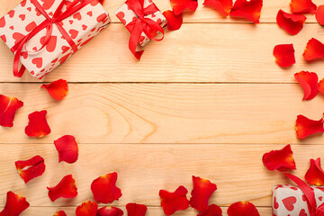 Frame made of gift for Valentine's Day and rose petals on wooden background
