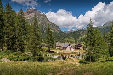 Stone house at Alpe Devero, Piedmont with trees and alps in the background