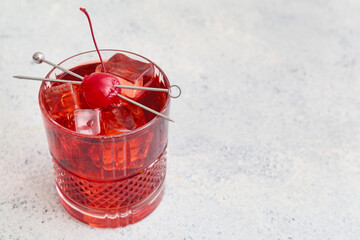 Glass of iced Manhattan cocktail on light background, closeup