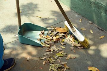 Woman; sweeping the road with a broom. He collects garbage in a dustpan; A sanitation worker sweeps...
