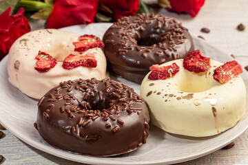 Handmade donuts on a light background in white and black chocolate. There are flowers nearby. Women's day, Valentine's day.