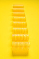 Set of hair curlers on yellow background, closeup