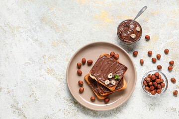 Plate of bread with chocolate paste and hazelnuts on light background
