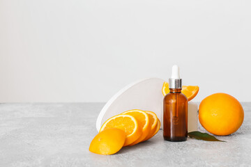 Bottle of essential oil and fresh orange on light background