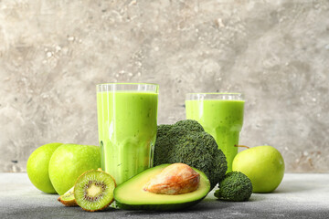 Glasses of healthy green juice and fresh ingredients on table