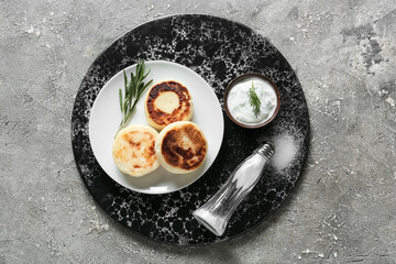 Plate with tasty cottage cheese pancakes and sauce on grey background