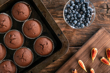 Fresh seasonal berries and homemade chocolate muffins on the table. Preparation for decoration, top view