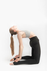 Camel Pose. Ustrasana. Young attractive woman practicing yoga on white background. Slender girl is engaged in gymnastics.
