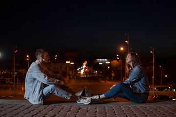 Guy and girl are sitting opposite each other on evening city background. Copy space