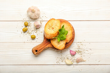 Board of tasty croutons on white wooden background