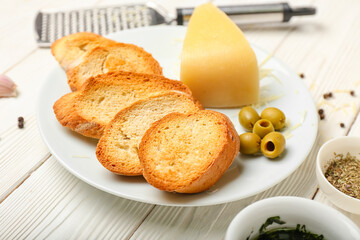 Plate of tasty croutons with cheese on white wooden background
