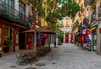 Fototapeta premium Old street with table of restaurant in Madrid, Spain. Architecture and landmark of Madrid, postcard of Madrid.