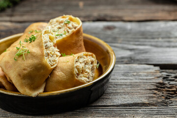 Savory crepe rolls, stuffed pancakes with ground meat filling. Traditional Russian Maslenitsa festival meal on wooden background