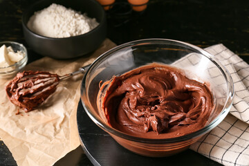 Bowl with fresh dough for preparing chocolate brownie on table