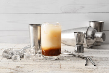 Glass of White Russian cocktail on light wooden background