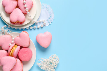 Composition with tasty heart-shaped macaroons and beads on blue background