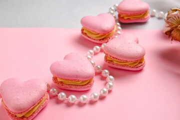 Tasty heart-shaped macaroons and beads on color background, closeup
