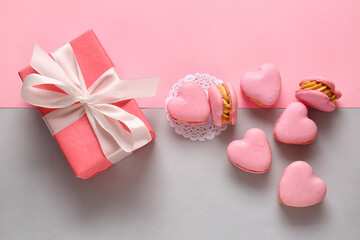 Tasty heart-shaped macaroons and gift box on color background