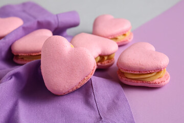 Tasty heart-shaped macaroons on purple background, closeup