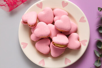 Plate with tasty heart-shaped macaroons on color background