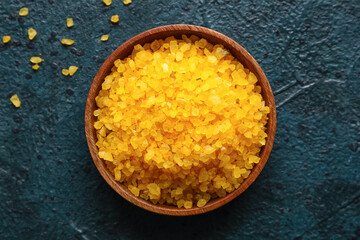 Bowl of orange sea salt on dark color background, closeup