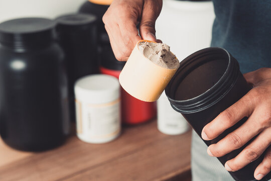 Hands holding scoop of whey protein and shaker with copy space healthy life.