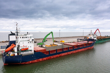 Fototapeta premium An aerial drone view of the industrial port in the Baltic Sea. There is a ships under load in the harbor. 