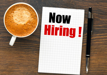 NOW HIRING words written in an office notebook.