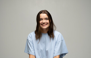 Close-up portrait of young brunette emotional woman in blue t-shirt with a big smile. Beautiful model posing in studio over white background.