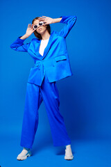 Fashion asian female model in blue suit, white boots and sunglasses.