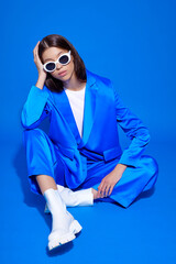 Fashion asian female model in blue suit, white boots and sunglasses.