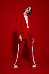 Fashion asian female model in red suit, white boots and sunglasses.