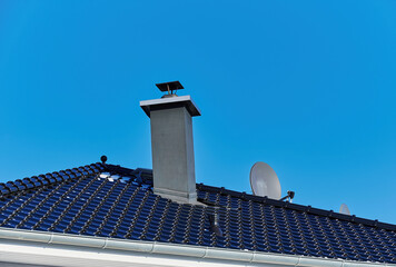 View of a roof with a chimney against a blue sky.