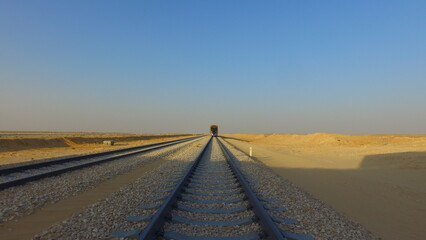 Fototapeta na wymiar train rail in the desert and the train approaching from far away