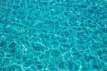 Fototapeta na wymiar Background of rippled pattern of clean water in a blue swimming pool.