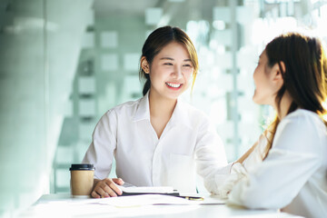 Obraz premium Female Asian smiles in support and puts her hand on her coworker shoulder.