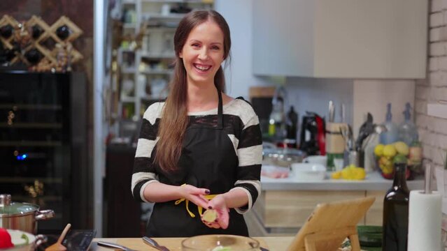 Young haopy laughing woman cooking in kitchen at home, healthy eating.