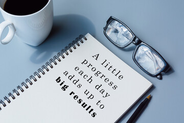 Motivational and inspirational quote on notepad with coffee, pen and glasses
