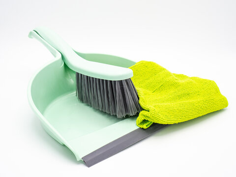 Small plastic dustpan, shovel and cleaning cloth on white background