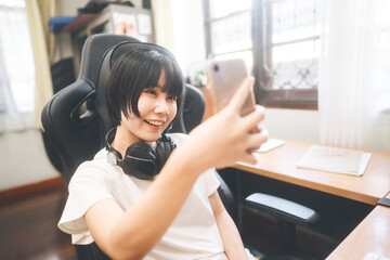 Young adult asian woman wear headphone using smart phone for social online content.